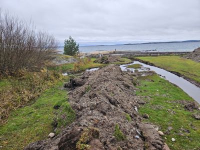 Fotografi av et utgravet område ved kysten, sannsynligvis en del av en byggeplass eller en utgravd kanal/grøft.