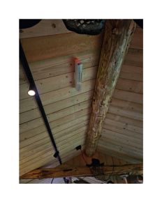 Fotografi av et tak med paneling, en stor tømmerbjelke og belysning.