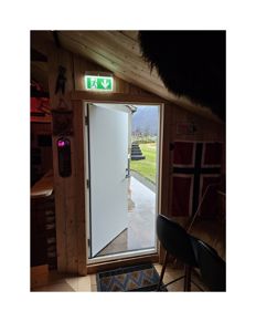 Fotografi av en døråpning med utsikt mot en hage og fjell.