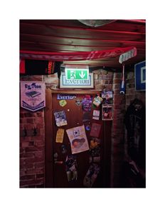 Fotografi av en dør med Everton-farger, plakater og et brannvarselskilt.