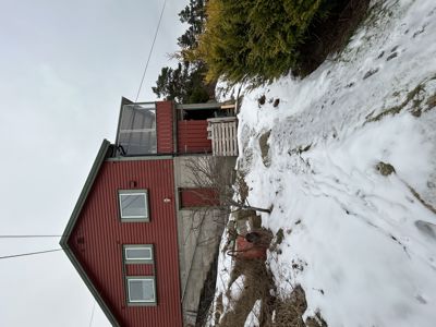 Fotografi av en rød bygning med etasje og glassfasade, sett fra siden med snø på bakken.