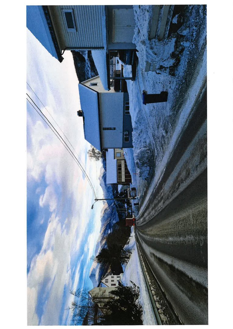 Fotografi av en snødekt vei med hus langs siden, sett fra et lavt perspektiv.