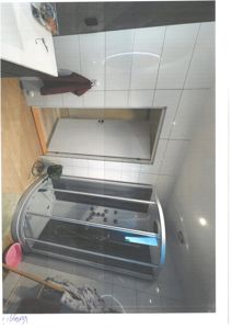 Fotografi av et bad med dusjkabinett, fliser og dør.