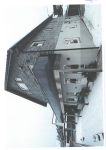 Fotografi av en ferdigbygd eller nesten ferdigbygd bolig sett fra siden. Bygningen har en kombinasjon av fasadematerialer (t.eks. panel og stein/tegl), og det er synlig snø på bakken og taket.