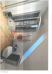 Fotografi av et bad med dusj, toalett og gulvfliser.