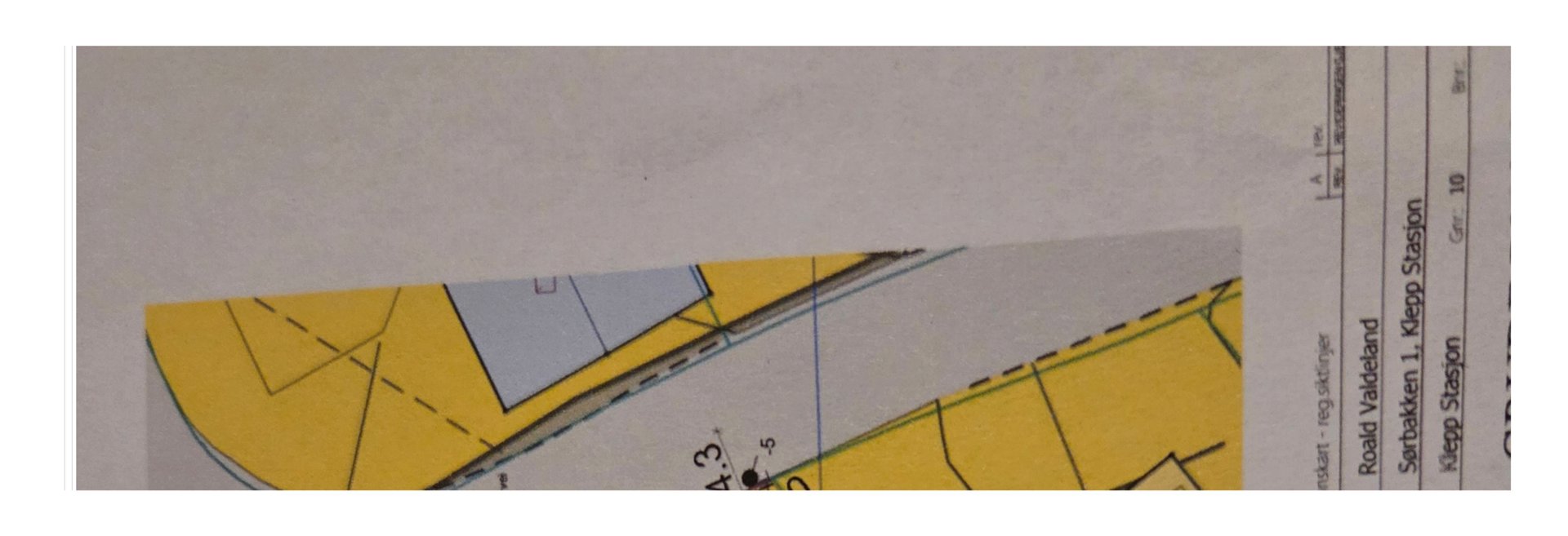 Dette er en del av en situasjonsplan eller tomtetekning. Den viser bygningens plassering i forhold til eiendomsgrenser, vegger og terrengforhold.