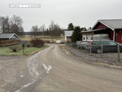Fotografi av en vei og tilhørende eiendom med bygninger og parkeringsplass.