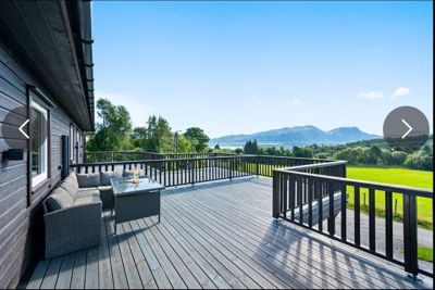 Fotografi av en terrasse med møbler og utsikt over en grønn dal og fjell.