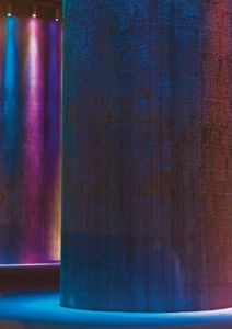 Fotografi av en stor, sylindrisk betongkonstruksjon (sannsynligvis en silo eller tank) med fargerikt lys (blå, lilla, rød) som skaper dramatisk effekt på overflaten.