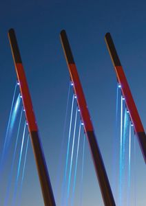 Fotografi av tre lyskaster med blå lysstråler mot en mørk himmel