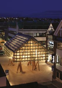 Fotografi av en bygning (Kunsthallen i Bergen) om natten, med lys innvendig og omgivende bymiljø.