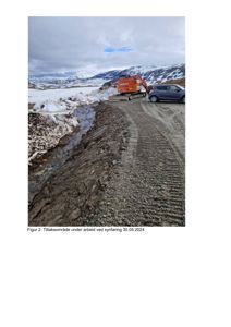 Fotografi av et utendørs område med snø, en grusvei, en graver og en bil. Bildet viser et tiltaksområde under arbeid.