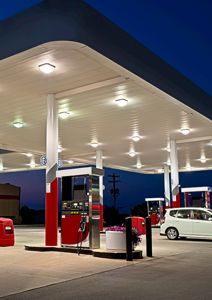 Fotografi av en bensinstasjon med tankpumper, søyler og en bil.