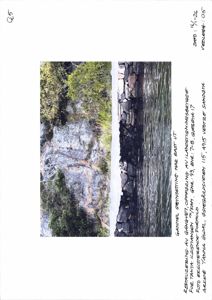 Fotografi av en steinmur langs vannet med vegetasjon i bakgrunnen.