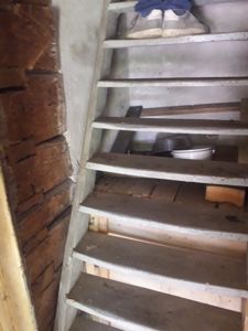 Fotografi av en trapp med tre trinn og en betongvegg, med sko og gjenstander på trinnene.