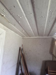 Fotografi av et roms innvendige hjørne med paneldekket tak og tapetsering på veggene.