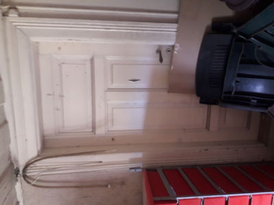 Fotografi av en hvit, panelert dør med dørkarm i et rom under ombygging eller renovering.