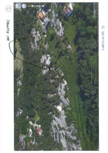 Satellittbilde fra Google Earth som viser et terreng med skog, fjell og flere hus i en bygd.