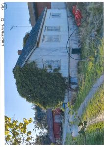 Fotografi av en eksisterende hvit malte trebygning med tak, vinduer og omgivelser.