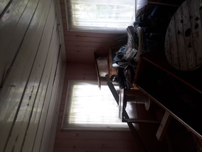 Fotografi av et rom med panelvegger, vinduer og møbler.