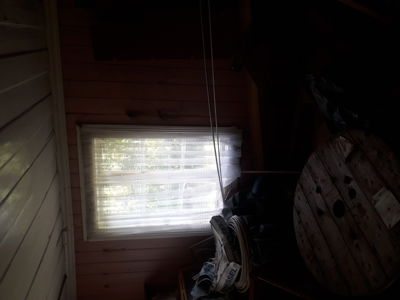 Fotografi av en mørk inngangsparti eller rom med vindu, trepanelvegger og gjenstander i forgrunnen.