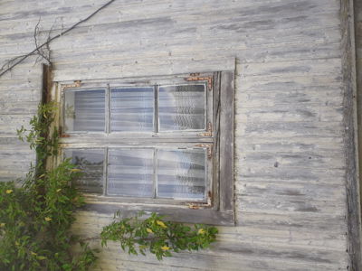Fotografi av en fasade med et gammelt vindu i treverk.