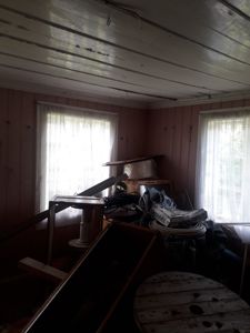 Fotografi av et roms indre med panelvegger, tak og vinduer. Rommet ser ut til å være i ferd med å bli renset eller omgjort.