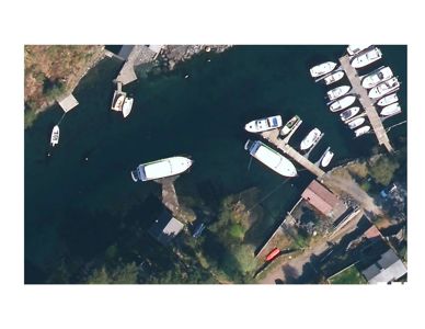 Flyfoto eller satellittbilde av en havn med båter, kai og omgivende terreng.