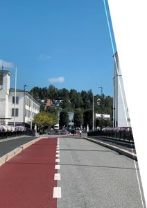 Fotografi av en gate med hvite bygninger, en rød sykkelvei og en person som sykler.