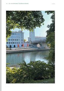 Fotografi av en bygning ved en elv eller kanal, sett fra en vinkel med trær i forgrunnen.