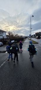 Fotografi av fire barn som går på en vei i et boligområde.