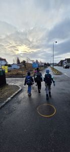 Fotografi av en gruppe barn som går på en vei i et boligområde.
