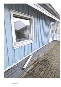 Fotografi av en blåmalt fasade med vindu og uteparti.