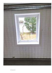 Fotografi av en hvit panelvegg med et vindu som ser ut på en hage.