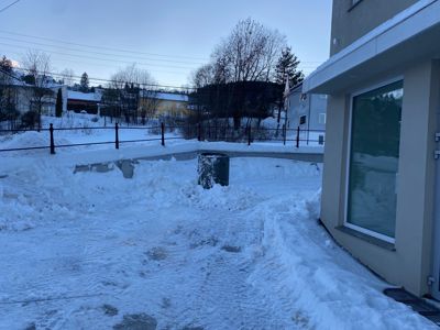 Fotografi av en snødekt uteplass ved en bygning.