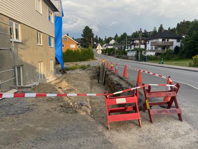 Fotografi av en byggeplass med en delvis ferdigstilt bygning, graving og veiarbeid.