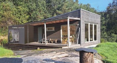 Fotografi av en ferdig eller nesten ferdig bygning (hus) sett fra utsiden, med omgivende natur.