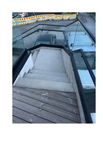 Fotografi av en trapp med glassrekkverk og tretrinn, sett fra øverst nedover.