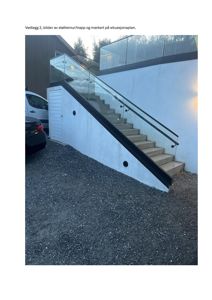 Fotografi av en utvendig trapp med glassbeslag og støttemur, sett fra bakkenivå.