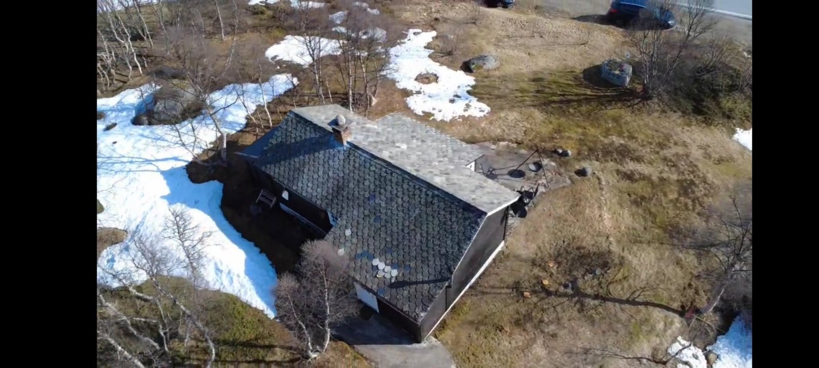 Fotografi av en bygning sett fra luften (dronebilde) med omgivende terreng og snø.