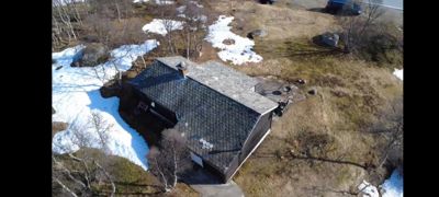 Fotografi av en bygning sett fra luften (dronebilde) med omgivende terreng og snø.