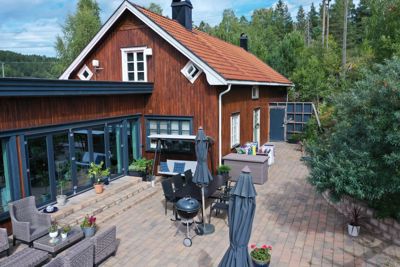 Fotografi av en eksisterende eller ferdig bygning med en moderne tilbygg, sett fra bakgårdsplassen med møbler og hage.