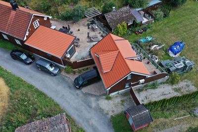 Luftfoto av en boligbebyggelse med flere hus, en vei, parkeringsplasser og hager.