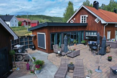 Fotografi av en nybygd eller renovert hytte med en tilhørende terrasse, møbler og omgivelser.