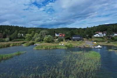 Fotografi av en eksisterende bygning ved vannet, sett fra et fjerntliggende perspektiv.