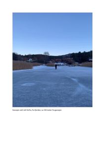 Fotografi av en garasje sett fra fjorden, med en person som går på isen i forgrunnen.