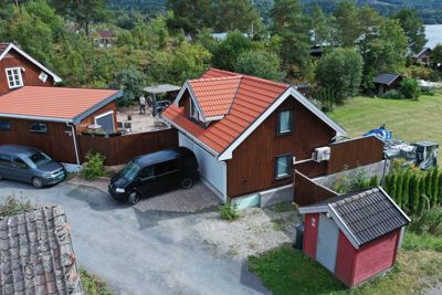 Fotografi av en eksisterende bolig med garasje, uthus og omgivelser sett fra et høyere utsyn.
