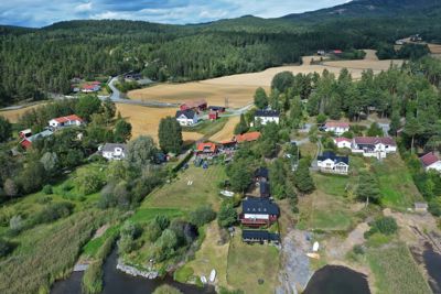 Luftfoto av et boligområde med hus, veier, skog og åker.