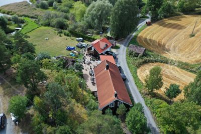 Luftfoto av en eiendom med to bygninger, en vei og omgivende natur.