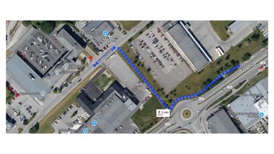 Satellittbilde (kart) som viser et område med bygninger, parkeringsplasser og veier, med en blå rute tegnet over.